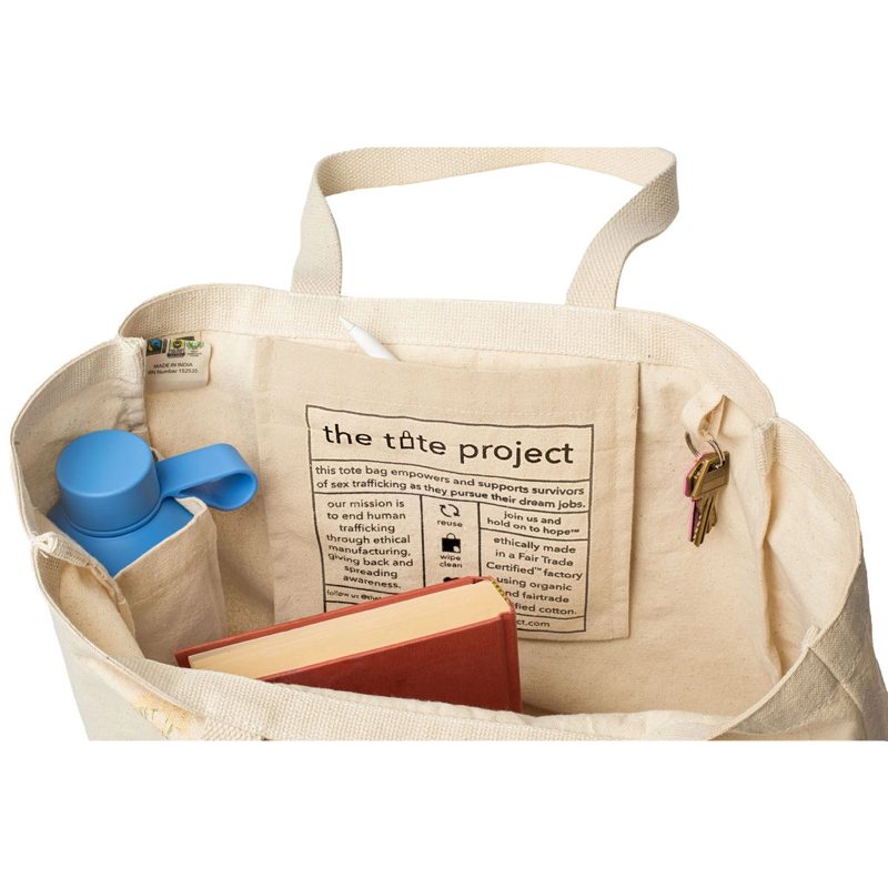 Beige tote bag with a book, blue water bottle, and keys on a white background