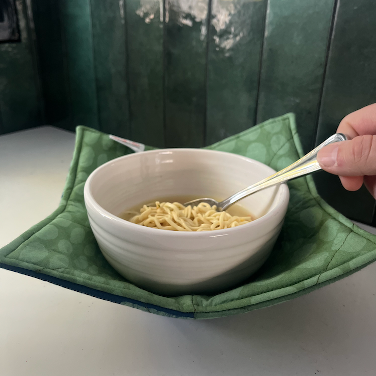 Global Mamas Bowl Cozy in Eclipse Green, a soft fabric cover designed to protect hands from hot bowls.