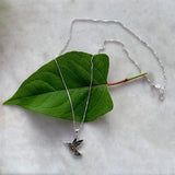 Abalone hummingbird necklace from Women's Peace Collection featuring a colorful, detailed bird pendant on a delicate chain.
