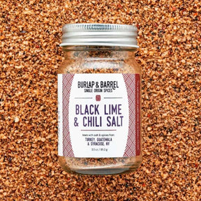 Burlap & Barrel black lime and chili sea salt in a clear jar, showing the vibrant salt blend with lime zest and chili flakes.