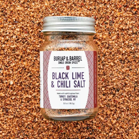 Burlap & Barrel black lime and chili sea salt in a clear jar, showing the vibrant salt blend with lime zest and chili flakes.