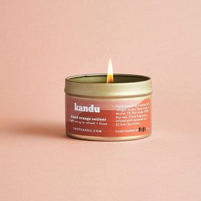 Kandu blood orange candle with a lit flame on a pink background