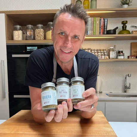 Burlap & Barrel Chef’s Best Friend, a versatile spice blend, displayed in a glass jar with fresh herbs and kitchen tools around it.