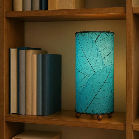 Sea blue cocoa leaf cylinder table lamp by Eangee, 12-inch height, featuring intricate leaf design and warm ambient lighting.