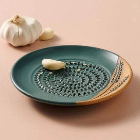 Green ceramic plate with garlic cloves on a beige background