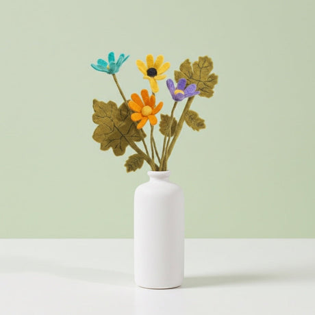 White vase with colorful felt flowers on a light green background