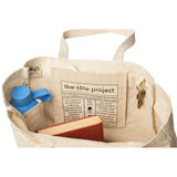 Beige tote bag with a book, blue water bottle, and keys on a white background