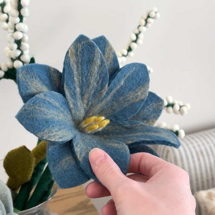 Blue felt flower with hand showing scale.