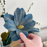 Blue felt flower with hand showing scale.