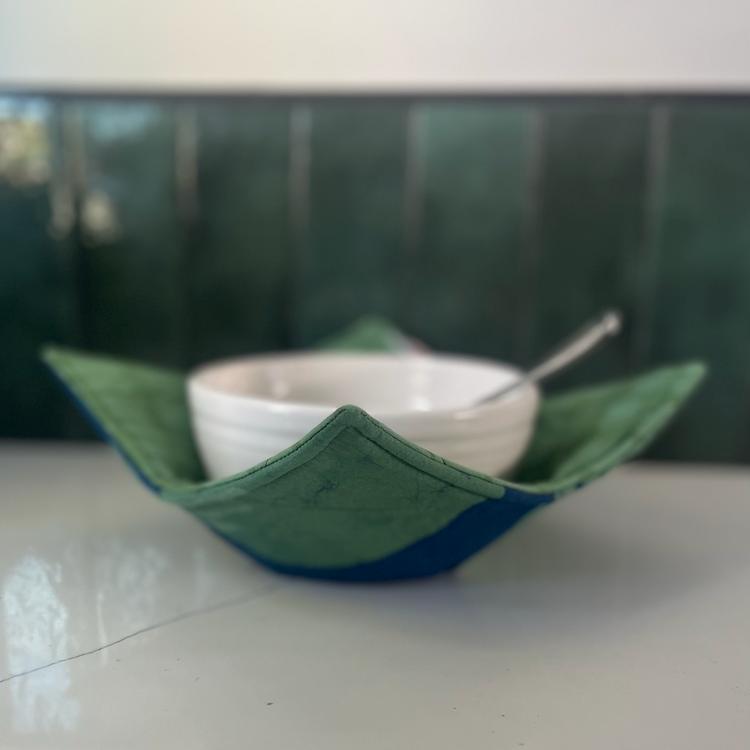 Global Mamas Eclipse Green bowl cozy with a vibrant green fabric cover designed to protect hands from hot bowls.