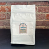 Louisiana Roasting Company cinnamon roll flavored 10 oz whole bean coffee in a bag, showcasing the aromatic beans.