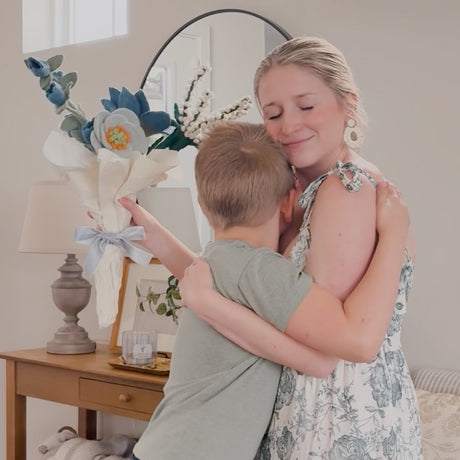 mother and son embracing with mother holding felt flower bouquet warpped as a gift for mother's day