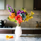 Colorful felt flower bouquet in a white vase on a kitchen counter.
