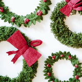 Decorative large wreath with red bow, featuring greenery and festive accents, by Gry & Sif for holiday decorating.