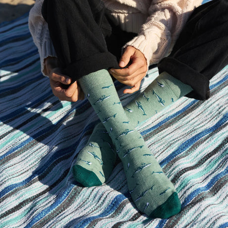 Pair of white cotton socks with whale protection logo from Conscious Step, designed to support whale conservation efforts.