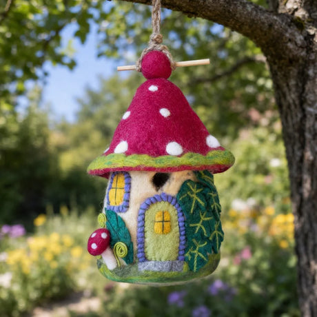 Colorful felt fairy house hanging from a tree with flowers and greenery in the background