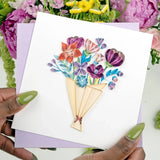 Hands holding a playful flower bouquet quilling card featuring colorful, handcrafted paper flowers and intricate quilling details.